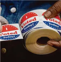  ?? Jessica Hill/Associated Press ?? A volunteer holds a sticker to give to a voter in Stamford.