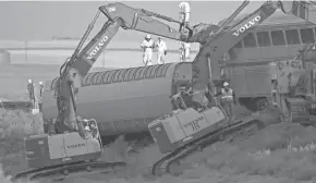  ?? TED S. WARREN/AP ?? Workers stand on a train car on its side as front-loaders prop up another train car on Sunday just west of Joplin, Mont.