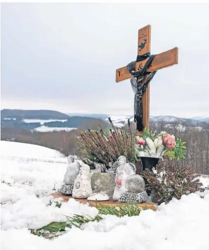  ?? FOTO: HARALD TITTEL/DPA ?? Ein Holzkreuz, Engelfigur­en und Blumen erinnern an der Gedenkstel­le auf einem Parkplatz bei Kusel an die 24-Jährige und den 29-Jährigen, die vor einem Jahr im Dienst getötet wurden.