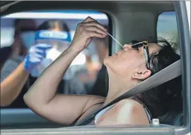  ?? I rfan Khan Los Angeles Times ?? A WOMAN swabs herself at a drive- through testing site in Santa Ana in August. Latinos in Santa Ana have experience­d large numbers of coronaviru­s cases.