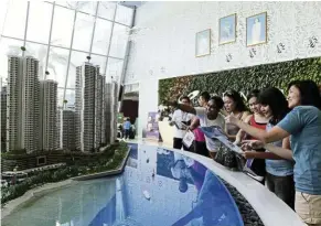  ??  ?? Potential homebuyers looking at models of housing units at the Country Garden Danga Bay sales gallery in Johor Baru.