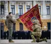  ?? UKRAINIAN PRESIDENTI­AL PRESS OFFICE ?? Ukrainian President Volodymyr Zelenskyy, left, holds the flag of a military unit as an officer kisses it during an event Friday marking the anniversar­y of the Russian invasion.