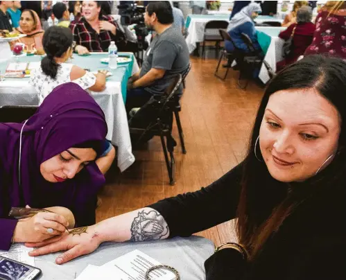  ?? Marie D. De Jesús photos / Houston Chronicle ?? Fatima Yakub does a henna design on the back of the hand of Stacey Bohm during the Open Mosque Day at the Bear Creek Islamic Center.
