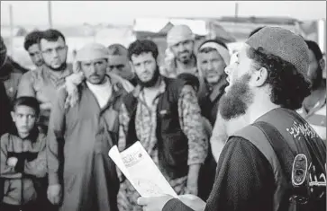  ?? Associated Press ?? A MEMBER of Islamic State’s “religious police” reads a verdict handed down by an Islamic court in Raqqah, Syria, sentencing accused adulterers to lashing. The photo was released last May by a militant website.