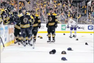  ?? AP PHOTO ?? As hats litter the ice, Boston Bruins’ David Pastrnak is congratula­ted at the bench after scoring his third goal of a game during the third period of a win over the Toronto Maple Leafs in Game 2 of their first-round playoff series in Boston Saturday.