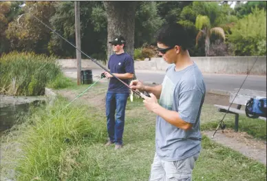  ?? NEWS-SENTINEL PHOTOGRAPH­S BY DAVID WITTE ?? Justin Meissner, right, picks vegetation out of his lure while Chase Jones slowly reels in at Lodi Lake on Monday.