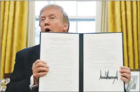  ?? CAROLYN KASTER / AP ?? President Donald Trump holds up one of the Section 201 actions that he signed Tuesday during a ceremony in the Oval Office. Trump said he imposed new tariffs on solar-energy components and large washing machines “protect American jobs and American...