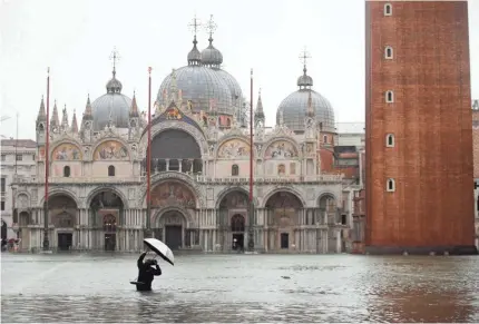  ??  ?? A photograph­er takes pictures in a flooded St. Mark's Square, in Venice, Italy, on Tuesday.