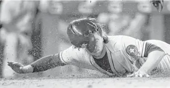  ?? Andy Clayton-King / Associated Press ?? It’s a dirty job, but Jake Marisnick is happy to score the Astros’ final run in the ninth inning Tuesday night.