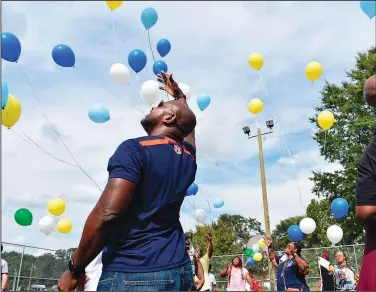  ?? (AP/Opelika-Auburn News/Alex Hosey) ?? Community members release balloons Oct. 2 in memory of Tramaris Bryant, Tyrone Brooks and Andrew Bryant at the basketball courts of the Covington Recreation Center in Opelika, Ala.