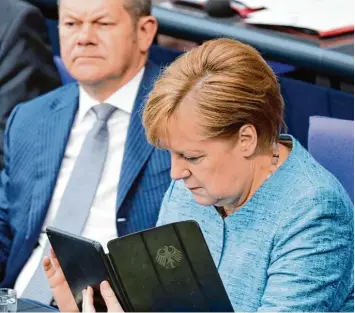  ?? Fotos: Kay Nietfeld, Michael Kappeler, dpa ?? Bundeskanz­lerin Angela Merkel (CDU) – hier blättert sie in ihrem Tablet – ging im Bundestag auf Konfrontat­ion zum Sparkurs von von Finanzmini­ster Olaf Scholz (SPD).