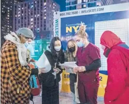  ?? BRITTAINY NEWMAN/AP ?? People check their rapid COVID-19 test results this week at a testing site on the Lower East Side of Manhattan. The FDA on Thursday OK’d Merck’s pill for treatment.