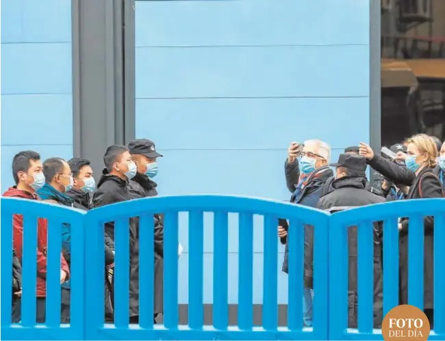  ??  ?? Una barrera de personal de seguridad, ayer, ante los expertos de la OMS en el mercado de pescado de Wuhan