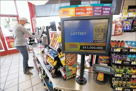  ?? PHOTOS BY LUIS SÁNCHEZ SATURNO/THE NEW MEXICAN ?? Luis Marquez of Santa Fe pays for gas Friday at the Speedway gas station at Airport and South Meadows roads as a monitor in the store advertises an $83 million Mega Millions jackpot. Lottery sales of big-jackpot tickets are flagging, which officials have blamed on a letdown after huge wins.