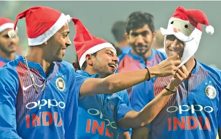  ?? — AFP ?? M.S. Dhoni, Kuldeep Yadav and Hardik Pandya sport Santa Claus caps at the presentati­on ceremony in Mumbai.