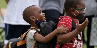  ?? MATT sTONE / HErALd sTAFF FiLE ?? ALL SET: Two brothers try on new backpacks and masks at a back-to-school distributi­on event. For older kids, masks may go away Oct. 1 if their schools reach a vaccinatio­n threshhold of 80%.