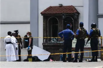  ??  ?? A foreign investigat­or (fourth left) talks with priests as soldiers stand guard at St. Anthony’s Shrine in Colombo. — AFP photo