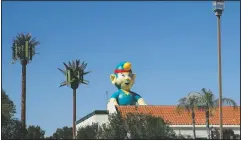  ??  ?? A giant inflatable elf stands next to cellphone towers disguised as palm trees in front of the Padre Murphy’s Sports Grill at a strip mall near the intersecti­on between Arizona Route 101 and Interstate 17 in Phoenix on March 9.