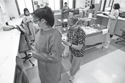  ?? PHOTOS BY MIKE DE SISTI / MILWAUKEE JOURNAL SENTINEL ?? Kimberly Lopez of West Allis has her gown tied as instructor Mary Kunicki, the program director for the surgical tech program, talks through the process of properly putting on a surgical gown during a surgical tech class at Milwaukee Area Technical College in Milwaukee. MATC has started in-person labs after the school was closed due to the coronaviru­s.