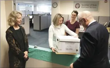  ?? AP PHOTO/ANDREW SELSKY ?? Lydia Plukchi of the Oregon Secretary of State’s office in Salem, Ore., accepts on Wednesday, a box containing 2,000 signatures backing a proposed ballot measure that would create the most comprehens­ive law in America requiring the safe storage of weapons, as worker Amanda Kessel, behind her, looks on.