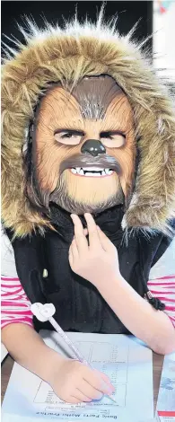  ?? PHOTO: CHRISTINE O’CONNOR ?? Wookie does homework . . . Scarlet Milner, of Dunedin, uses one hand to keep her Chewbacca mask in place while doing her maths homework.