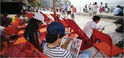  ?? — AFP photos ?? People read books outside a library, open during the summer, in Etretat, northweste­rn France.