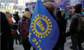  ??  ?? A person carries a UAW flag during a May Day rally in New York City. Photograph: Andrew Kelly/Reuters