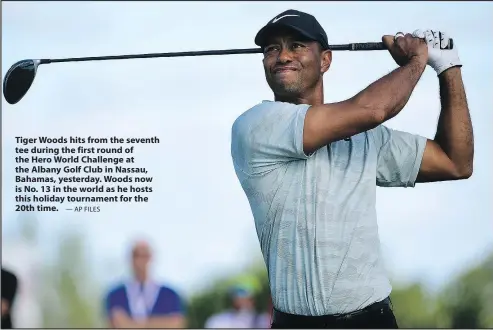  ?? — AP FILES ?? Tiger Woods hits from the seventh tee during the first round of the Hero World Challenge at the Albany Golf Club in Nassau, Bahamas, yesterday. Woods now is No. 13 in the world as he hosts this holiday tournament for the 20th time.