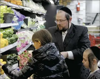  ?? AP photo ?? Eliot Spitzer selects vegetables at a kosher supermarke­t with two of his seven children, Faigy (right) and Abba in the Hasidic Jewish section of Brooklyn’s Williamsbu­rg neighborho­od in New York on Tuesday. Some U.S. Jewish families observing the Passover are struggling to pay for matzo, eggs and gefilte fish and worry about how soaring inflation is driving up prices during one of the most important holidays for Jews.