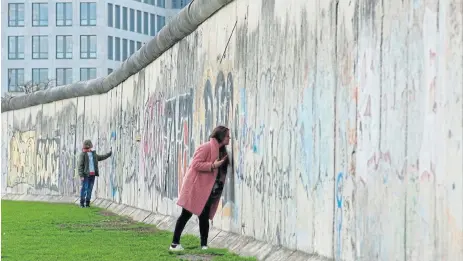  ?? /Fabrizio Bensch ?? Concrete history: People touch remains of the Berlin Wall at the memorial on Bernauer Strasse in Berlin, Germany ahead of the 30th anniversar­y of the fall of the wall and reunificat­ion of the east and west.