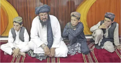  ??  ?? KABUL: In this photo taken on Tuesday, July 25, 2017, Mohammed Naseer, with black turban, and three children wait for their food in the prayer area of a Pizza Restaurant. — AP