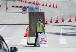  ?? AP PHOTO/DAMIAN DOVARGANES ?? A Los Angeles traffic control officer directs vehicles to an alternativ­e entrance to the Dodgers Stadium vaccinatio­n site in Los Angeles last week.