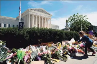  ?? Jose Luis Magana / AFP via Getty Images ?? A child places a flower outside of the U.S. Supreme Court after the passing of Justice Ruth Bader Ginsburg, in Washington, D.C., on Saturday. Ginsburg died Friday, opening a vacancy on the high court expected to set off a pitched political battle at the peak of the presidenti­al campaign.