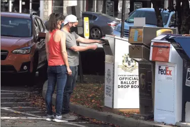  ?? Ned Gerard / Hearst Connecticu­t Media ?? A couple stop to deliver their election ballots into an official drop box in front Milford City Hall, in Milford on Wednesday.