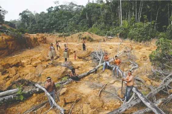  ?? UESLEI MARCELINO/ REUTERS ?? Indigenous people from the Mura tribe pause in a deforested area within unmarked Indigenous lands in the Brazilian rainforest.