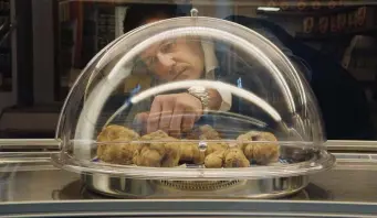  ??  ?? LUXURY GOODS: Dealer Gianfranco Curti inspects a array of truffles under glass. Below, elderly truffle hunter Aurelio Conterno spoils his dog, Birba.