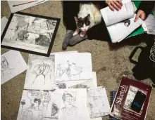 ??  ?? Dakota Koppenol, with one of his cats, Pepper, flips through his sketchbook­s, which hold years’ worth of artwork.