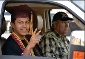  ??  ?? Anthony Santos flashes a smile and a peace sign as he rolls by to get his diploma at the Citrus High School drive-thru graduation ceremony on Friday night.