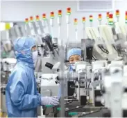  ?? AP PHOTO/MARK SCHIEFELBE­IN ?? Employees wearing protective equipment work at a semiconduc­tor production facility in Beijing last year.