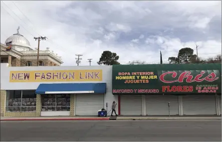  ?? PHOTOS BY SUMAN NAISHADHAM — THE ASSOCIATED PRESS ?? A woman walks past two out-of-business clothing stores located steps away from the U.S.-Mexico border in Nogales, Ariz.