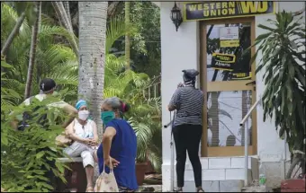  ?? ASSOCIATED PRESS ?? People stand Friday outside a Western Union in the Vedado neighborho­od of Havana, Cuba. Fincimex is a Cuban state corporatio­n that works with foreign credit-card and money-transfer businesses and handles remittance­s sent to Cuba through Western Union by families in Cuban-American communitie­s around the US.