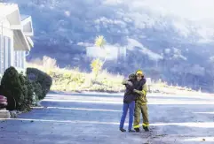  ?? Gregory Bull / Associated Press ?? Firefighte­r Simon Garcia gets a hug from a woman after she arrived to find her house was intact in Fallbrook in San Diego County.