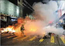  ?? KIN CHEUNG/AP ?? Firefighte­rs put out a fire set by protesters during a demonstrat­ion Friday in Mong Kok, in Hong Kong. About 2,000 angry protesters surrounded the police station in the district.