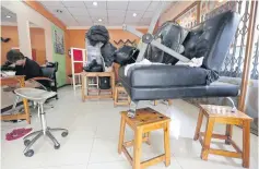  ??  ?? BELOW Items of furniture are raised on stools and tables at a hair salon in Muang district of Phetchabur­i. Local residents are finding ways to secure their homes and mitigate the effects of an imminent flood triggered by an upstream dam spillover.