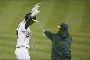  ?? AP photo ?? Oakland’s Matt Olson is splashed with water as he approaches home plate after hitting a grand slam in the 10th inning to give the A’s a 7-3 win over the Los Angeles Angels on Friday.