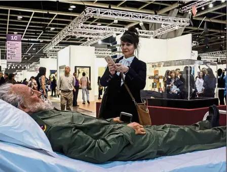  ?? — AFP ?? Dead ringer: A woman taking photos of Chinese artist Shen’s Castro, part of his ‘ Summit’ project, at Art Basel in Hong Kong.