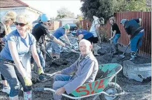  ??  ?? Digging in: Volunteers from Mt Hutt help New Brighton residents clean up liquefacti­on in Christchur­ch.