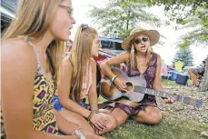  ?? PHOTOS BY SETH WENIG/AP ?? (R-L) The Lescinski sisters, from left, Kristi, 19; Jaime, 17; and Emily, 13, sing together in the parking lot while waiting for the gates to open at a Woodstock 50th anniversar­y event in Bethel, New York on Thursday.
