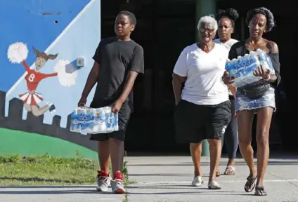  ?? Kathy Willens/Associated Press ?? Rahjiah McBride, of Chester, Pa., right, and her son, left, help her Newark relatives carry bottled water from the Boylan Street Recreation Center this week in Newark, N.J.
