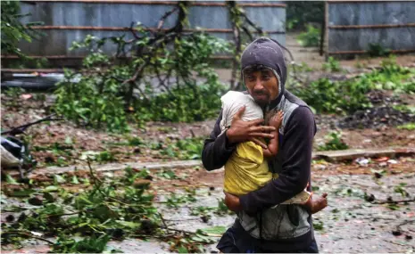  ?? Reuters ?? A man carries a child to a shelter yesterday after Cyclone Mocha made landfall in Teknaf, southern Bangladesh
